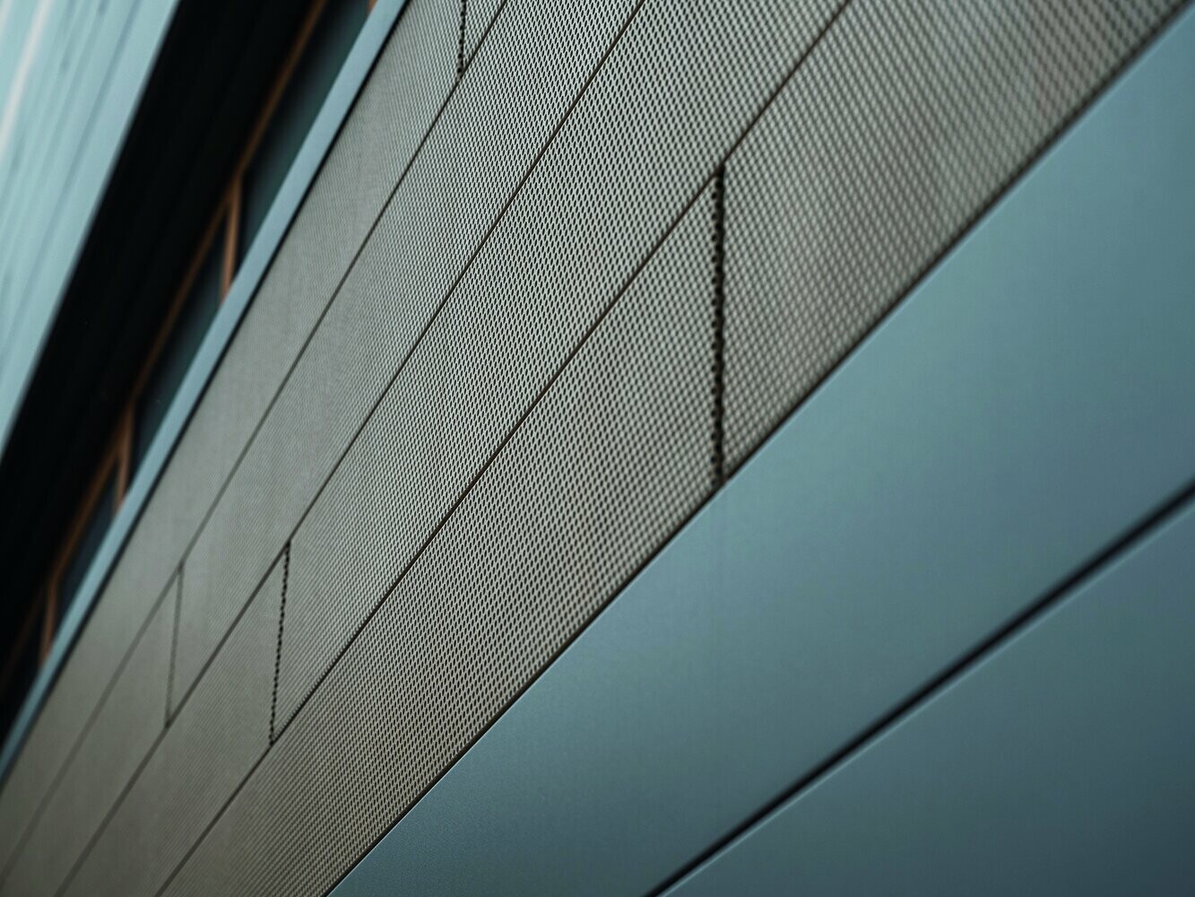 Die Fassadenpaneele von PREFA, Siding, sind jetzt auch in perforierter, also gelochter Ausführung erhältlich, hier sind sandbraune gelochte Elemente mit grauen Paneelen kombiniert. 