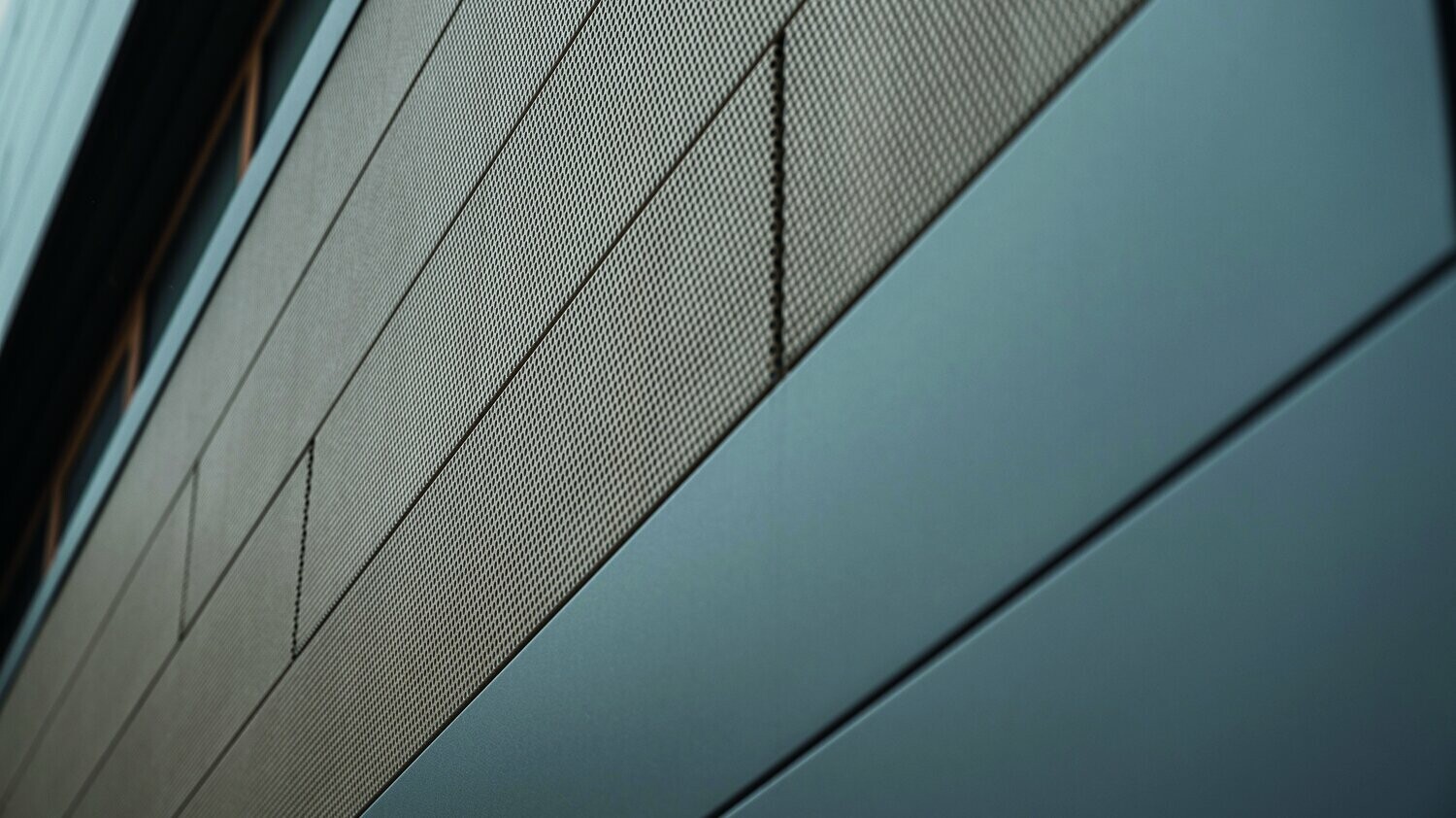 Die Fassadenpaneele von PREFA, Siding, sind jetzt auch in perforierter, also gelochter Ausführung erhältlich, hier sind sandbraune gelochte Elemente mit grauen Paneelen kombiniert. 