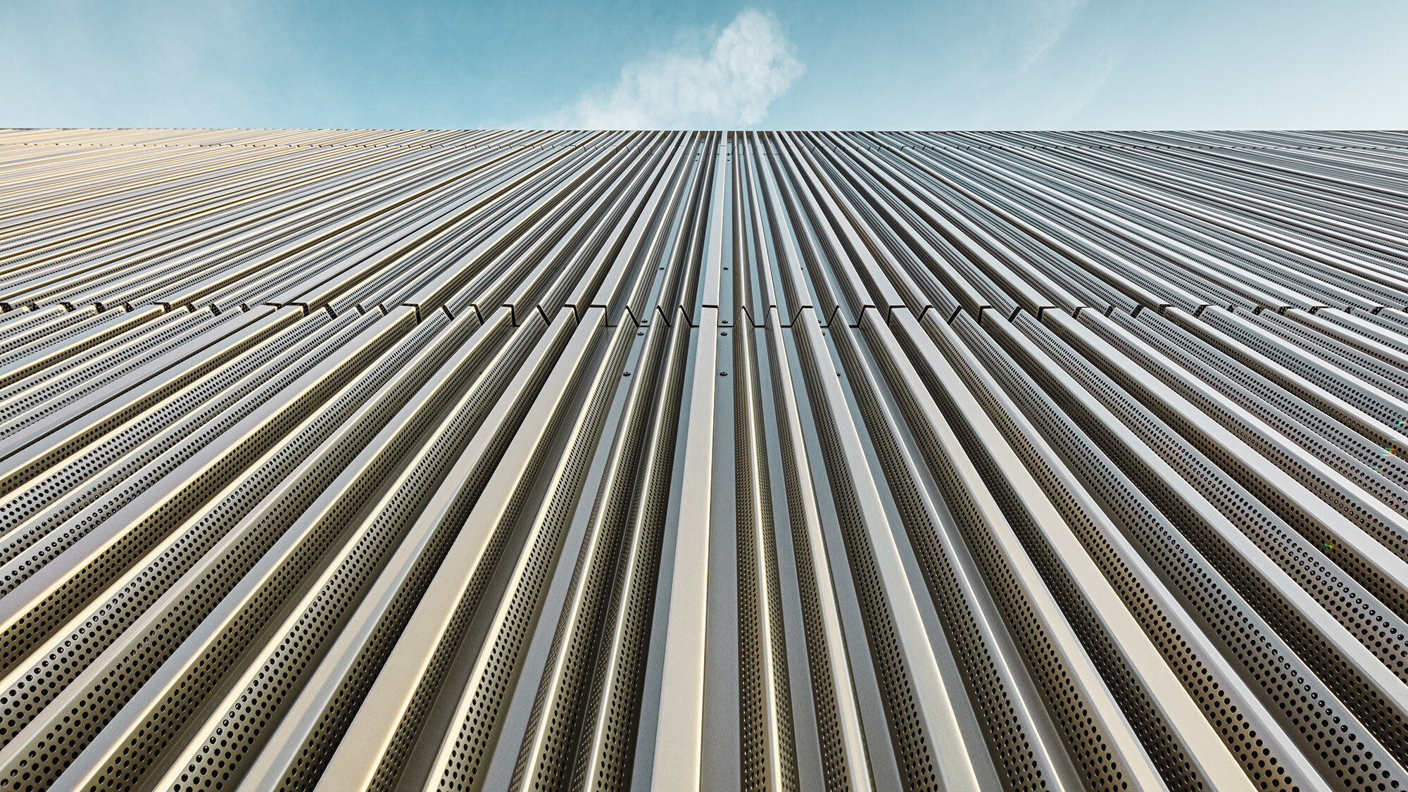 Die Aluminiumfassade mit Profil aus der Froschperspektive, darüber der Himmel.