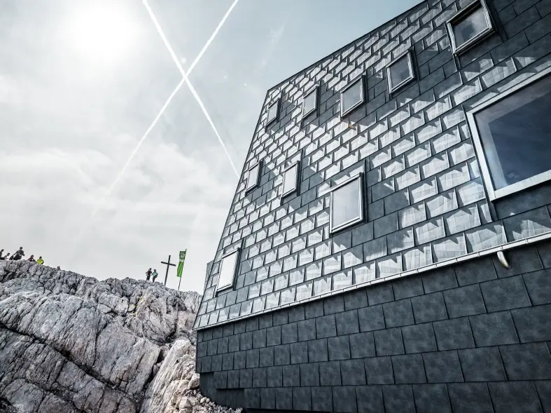 seitliche Ansicht der Seethalerhütte auf 2.740 Metern Höhe vor blauem Himmel, verkleidet mit PREFA Dach- und Fassadenpaneelen FX.12 in P.10 Steingrau