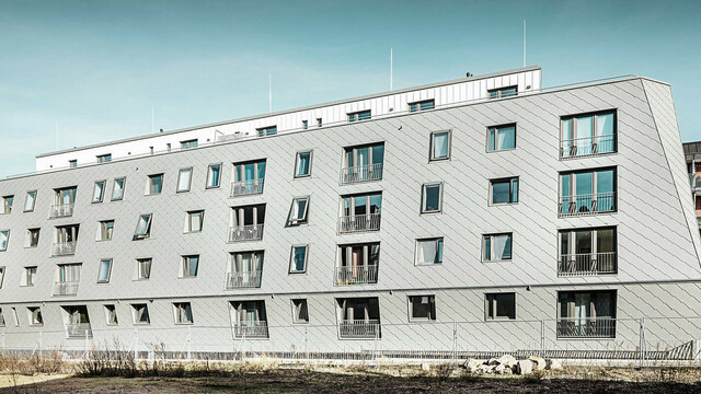 Das Bild zeigt das Haus im Harburger Binnenhafen bei Tag, welches mit PREFA Wandrauten 44x44 und Prefalz eingedeckt wurde.