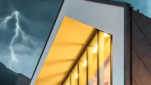 Gewitterstimmung und Blitz mit einem Haus mit PREFA Dach und Fassade im Vordergrund. Mit PREFA ist Ihr Haus gut geschützt.