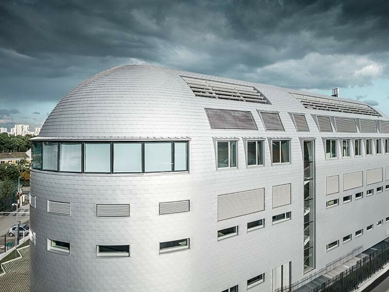 Das moderne Gebäudedesign des Technologie-Centers in Paris wurde mit PREFA Dach- und Wandschindeln eingedeckt um die abgerundete Form hervorzuheben