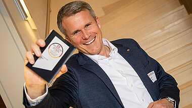 Tobias Götz, Geschäftsführer von PREFA, hält die Auszeichnung des Life & Living Award 2026 lächelnd in die Kamera.