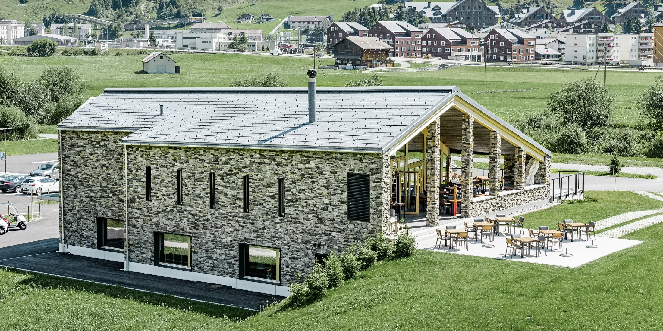 Modernes Club Haus des Golfplatzes in Andermatt mit Steinfassade und PREFA Dachpaneel FX.12 aus Aluminium in steingrau