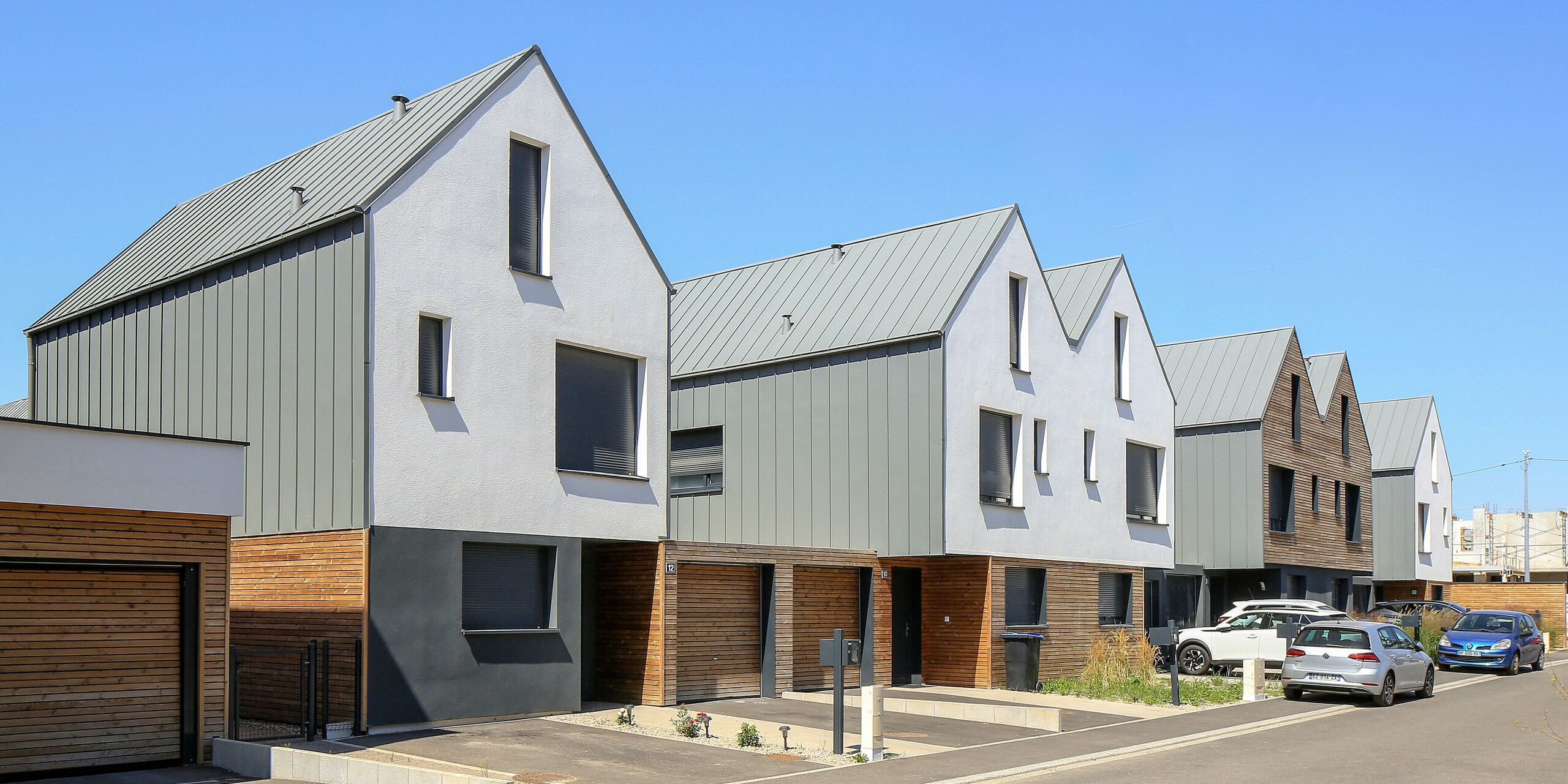 PREFALZ in Hellgrau zieht sich über die Fassaden und Satteldächer einer Reihenhaus-Siedlung in Mundolsheim. Die einheitlichen Gebäudehüllen aus Aluminium schaffen ein harmonisches Gesamtbild.