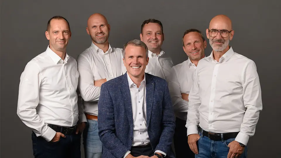 Geschäftsleiter von PREFA Deutschland, Tobias Götz, umgeben von den nun fünf Außendienst-Vertriebsleitern. Alle tragen weiße Hemden, lächeln und stehen lässig um den Geschäftsführer herum.