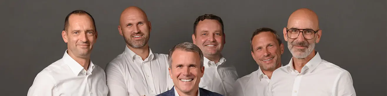 Geschäftsleiter von PREFA Deutschland, Tobias Götz, umgeben von den nun fünf Außendienst-Vertriebsleitern. Alle tragen weiße Hemden, lächeln und stehen lässig um den Geschäftsführer herum.