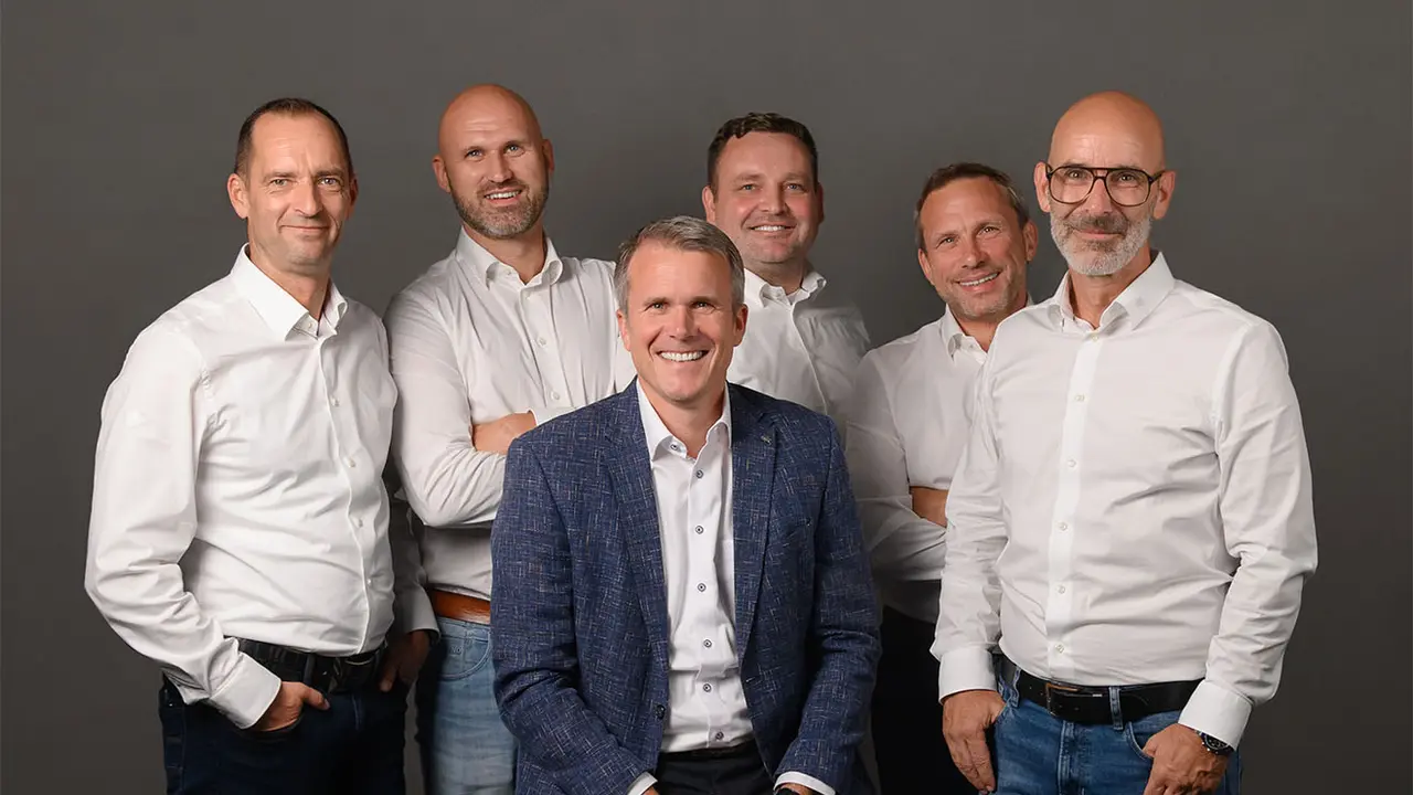 Geschäftsleiter von PREFA Deutschland, Tobias Götz, umgeben von den nun fünf Außendienst-Vertriebsleitern. Alle tragen weiße Hemden, lächeln und stehen lässig um den Geschäftsführer herum.