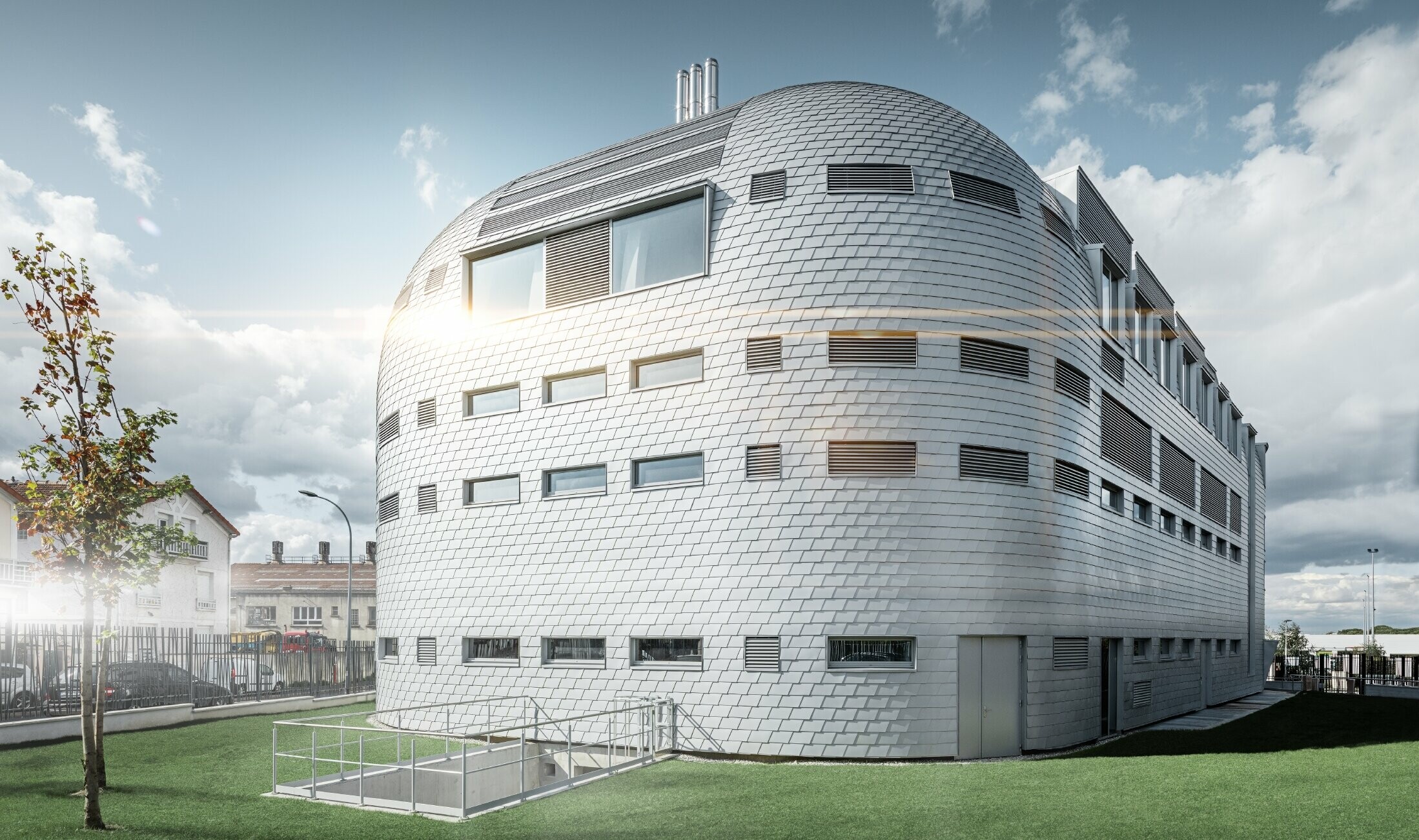 Modernes Bürogebäude mit den glänzenden Alu-Schindeln von PREFA in Silbermetallic eingedekt; Die Kuppel wurde mit handgefertigten Dachschindeln verkleidet.
