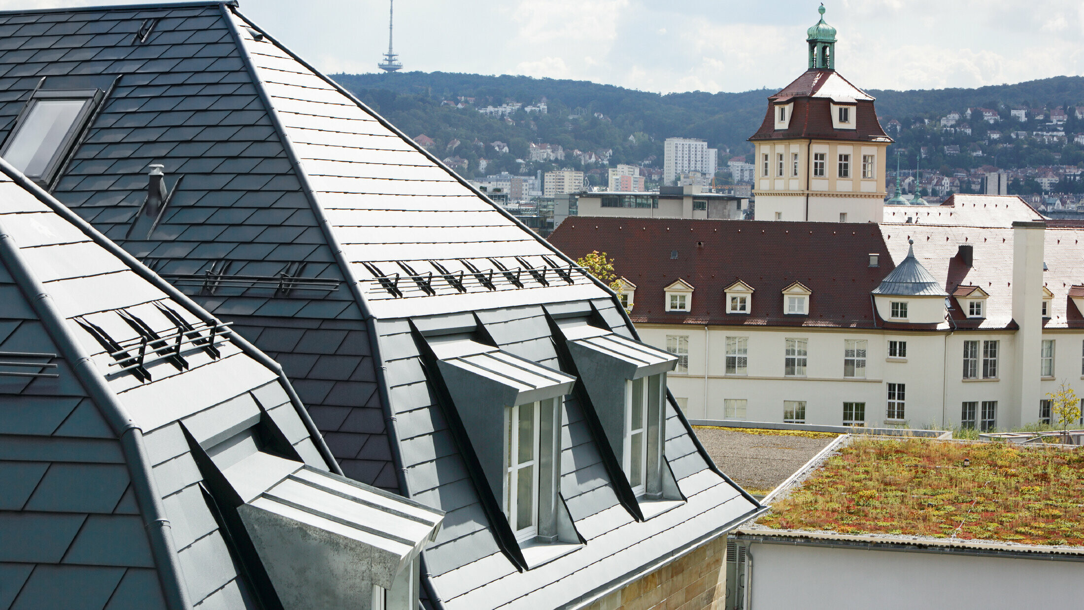 Altes Stadthaus in Stuttgart mit geknicktem Dach und vielen Gaubenfenstern, eingedeckt mit der Aluschindel von PREFA in P.10 Anthrazit