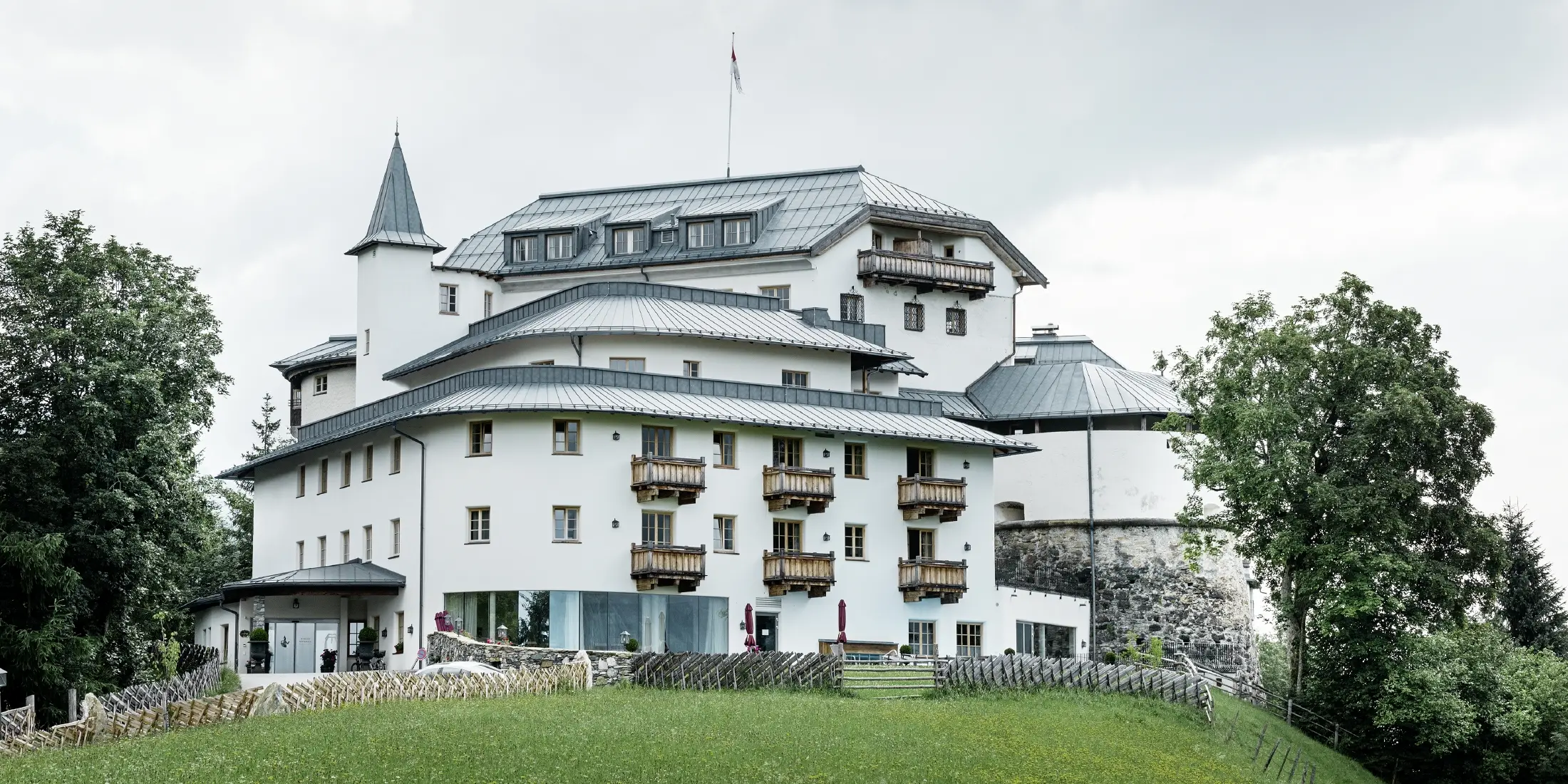 Schloss Mittersill, umgeben von Bäumen und Bergen, mit einem renovierten Prefalz Dach in Steingrau