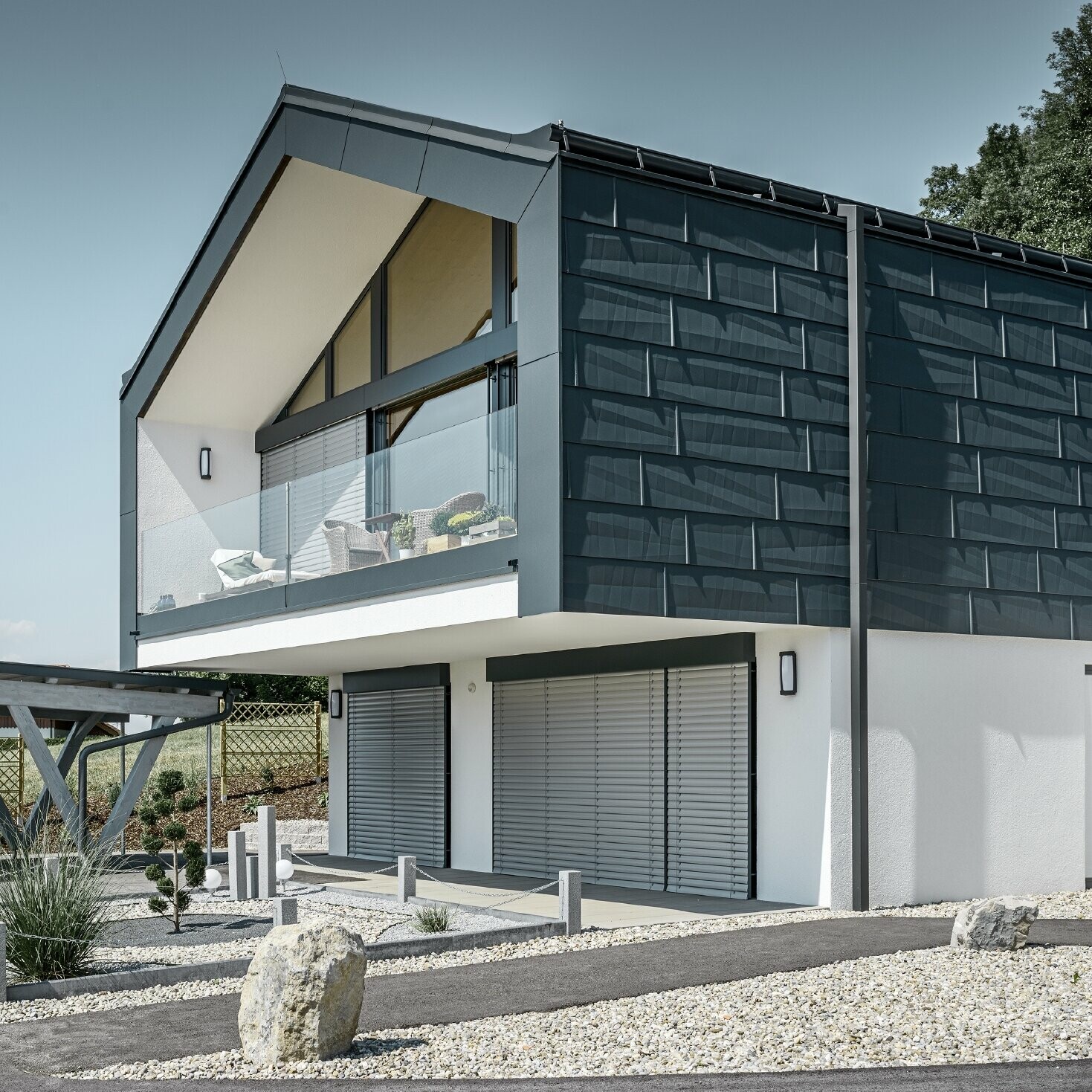 Modernes Mehrfamilienhaus mit einer großen Fensterfront, Dach und Fassade wurden mit dem Dach- und Fassadenpaneel FX.12 in anthrazit von PREFA bekleidet