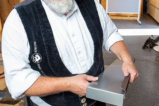 Detailaufnahme eines Aluminiumteils, der für die Laibung im oberen Fensterbereich durch den PREFA Techniker umgekantet wird.