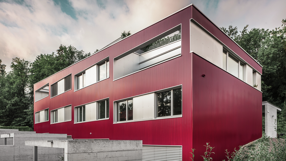 Seitliche Außenaufnahme des Wohnhauses am Zürichsee in der Schweiz, verkleidet mit der PREFA Profilwelle in der Farbe Weinrot