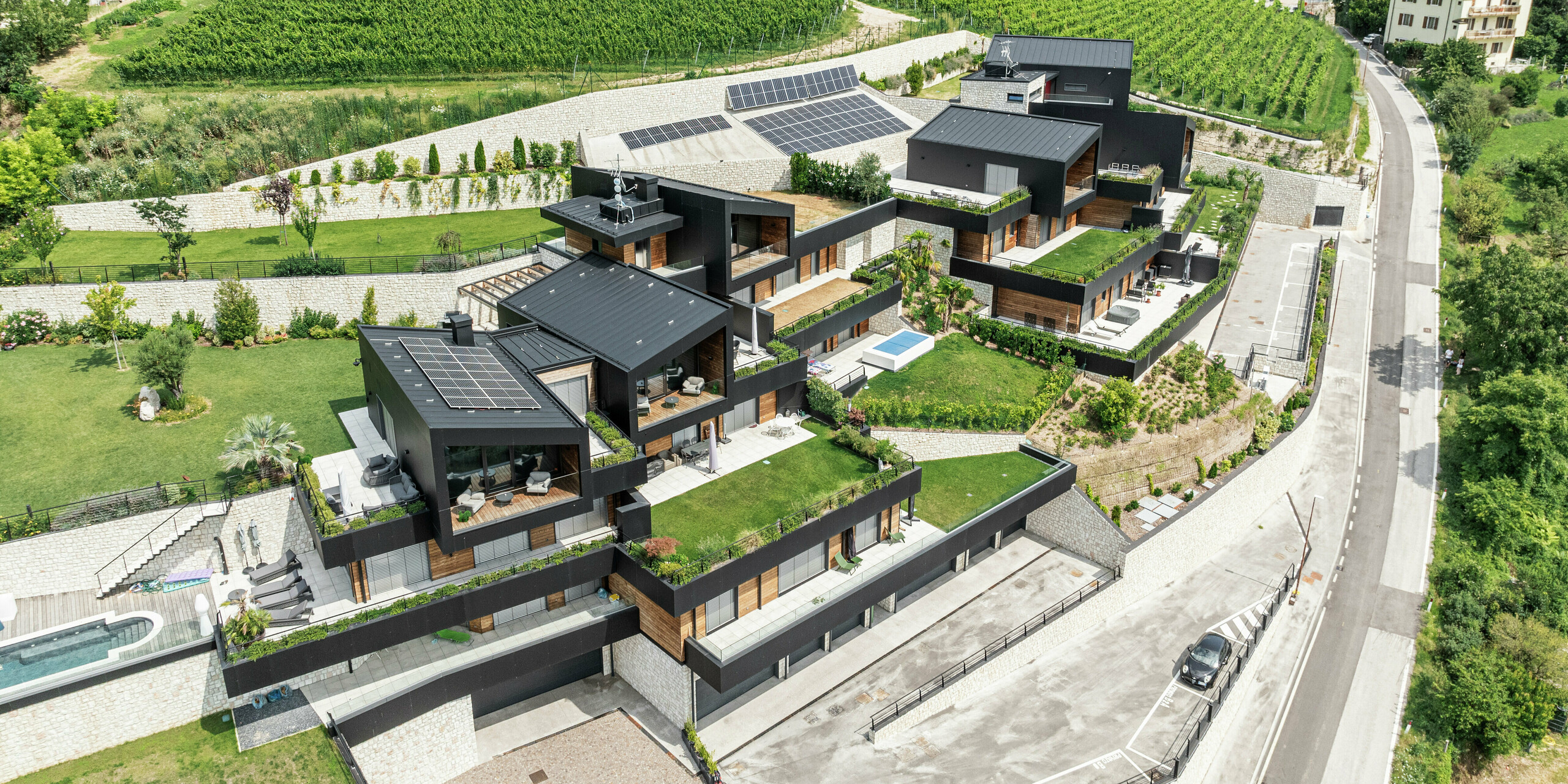 Eingebettet in die malerische Hügellandschaft von Trient verbindet diese exklusive Wohnanlage nachhaltiges Bauen mit modernem Design. Die Fassaden aus PREFA Aluminiumn Verbundplatten in P.10 Schwarz und die Dächer aus PREFALZ bieten höchsten Witterungsschutz und sorgen für eine edle und langlebige Optik. Großzügige Terrassen, eine gepflegte Bepflanzung und Photovoltaikanlagen unterstreichen das umweltfreundliche Konzept. Die harmonische Einbettung in die Natur sowie luxuriöse Details wie private Pools und gepflegte Gärten machen dieses Wohnprojekt zu einem einzigartigen Wohlfühlort.