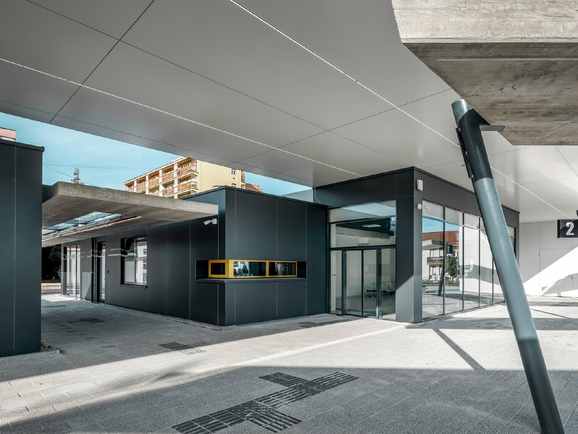 Überdachter Bereich des Busbahnhofs Lenti; Die Untersicht der Überdachung ist mit PREFABOND Verbundplatte in Reinweiß verkleidet, die Fassadenelemente beim Eingangsbereich in P.10 Anthrazit.