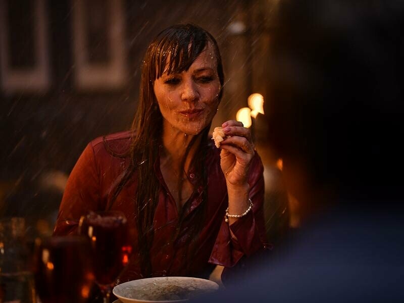 Frau sitzt mit ihrem Mann bei einem romantischen Dinner zu Hause. Beide sind nass, da es im Haus regnet. Ausschnitt aus dem neuen PREFA Werbespot.