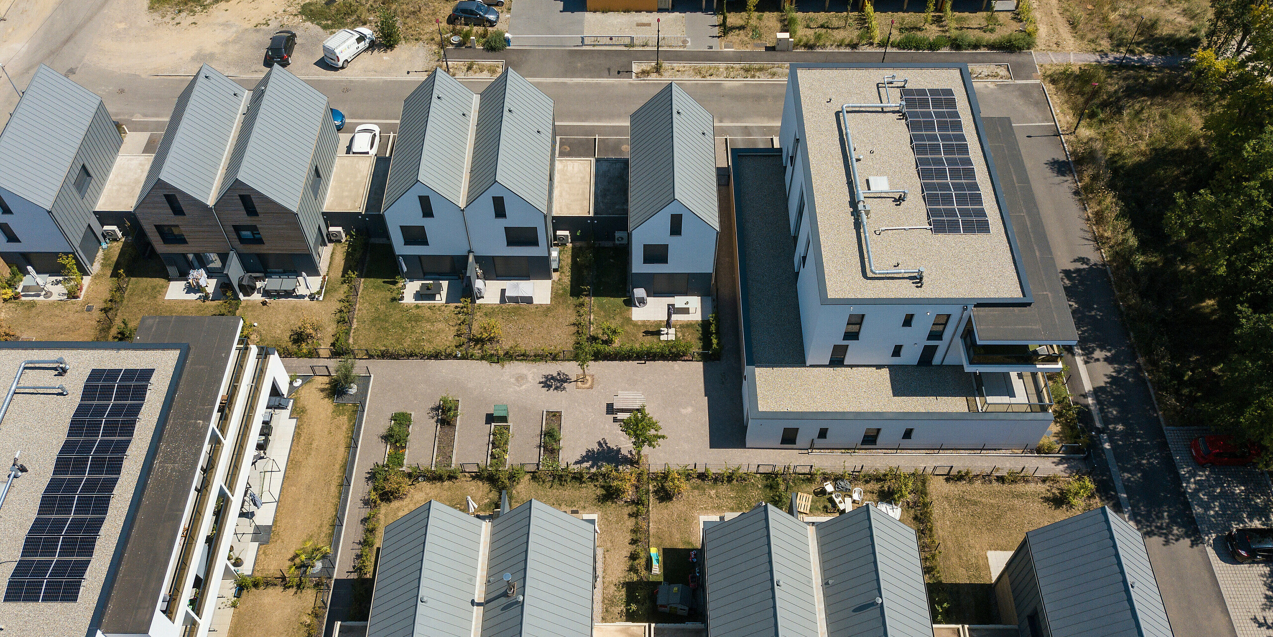 PREFALZ in Hellgrau zieht sich über die Fassaden und Satteldächer einer Reihenhaus-Siedlung in Mundolsheim. Die einheitlichen Gebäudehüllen aus Aluminium schaffen ein harmonisches Gesamtbild.