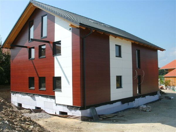 Haus in Holzoptik, mit Fassenteilen aus PREFA Verbundplatten in der Farbe Reinweiß.