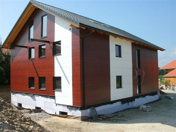 Haus in Holzoptik, mit Fassenteilen aus PREFA Verbundplatten in der Farbe Reinweiß. 