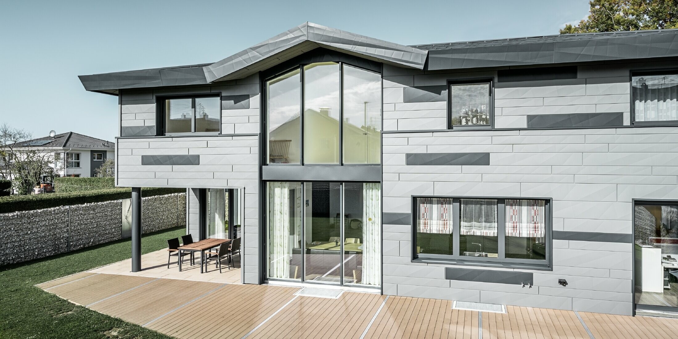 Terrassenansicht des Einfamilienhauses in Türkheim. Große Fenster zieren die zweifärbige Aluminiumfassade von PREFA.