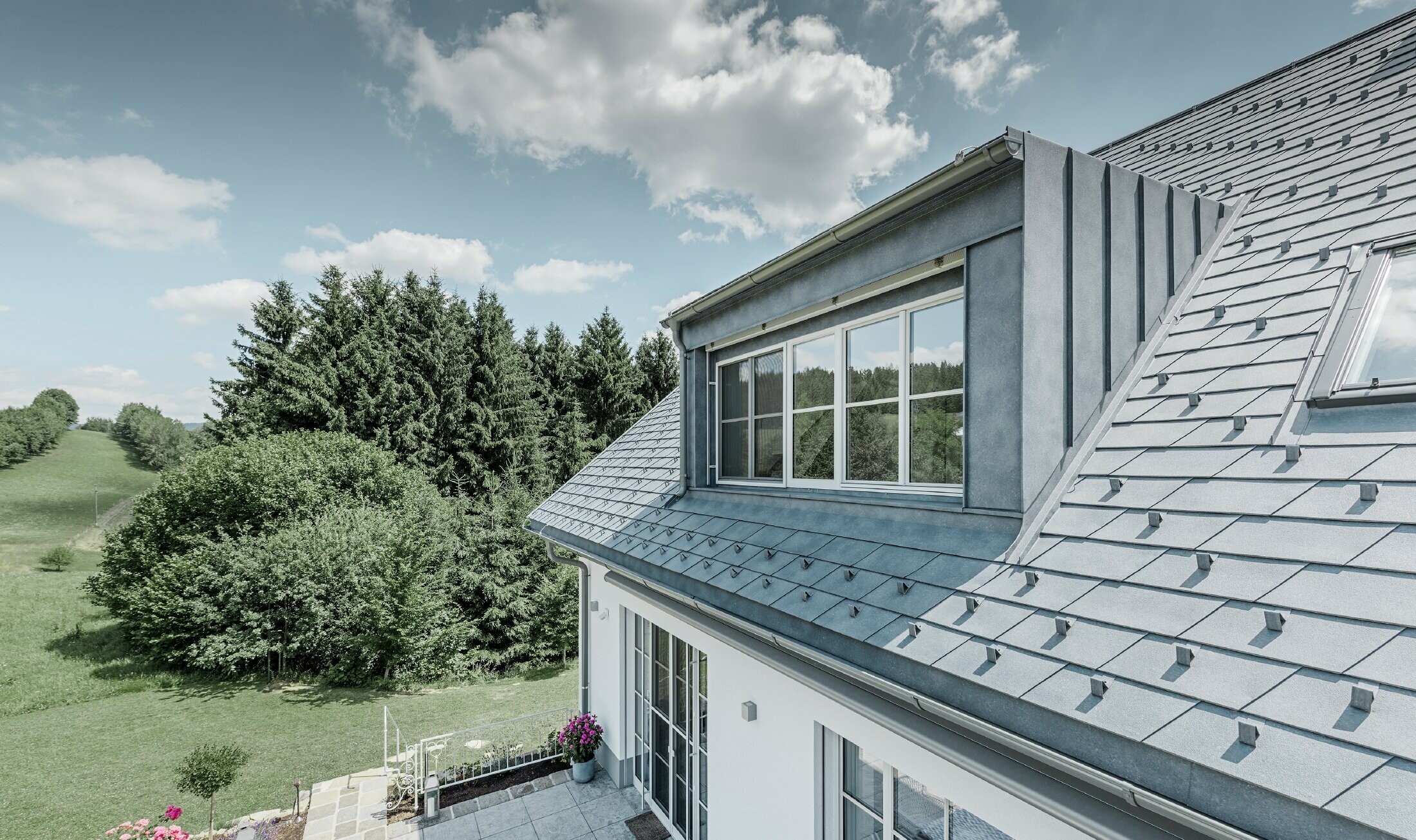 Rückansicht des neu sanierten Bauernhauses mit der PREFA Dachschindel in Steingrau.