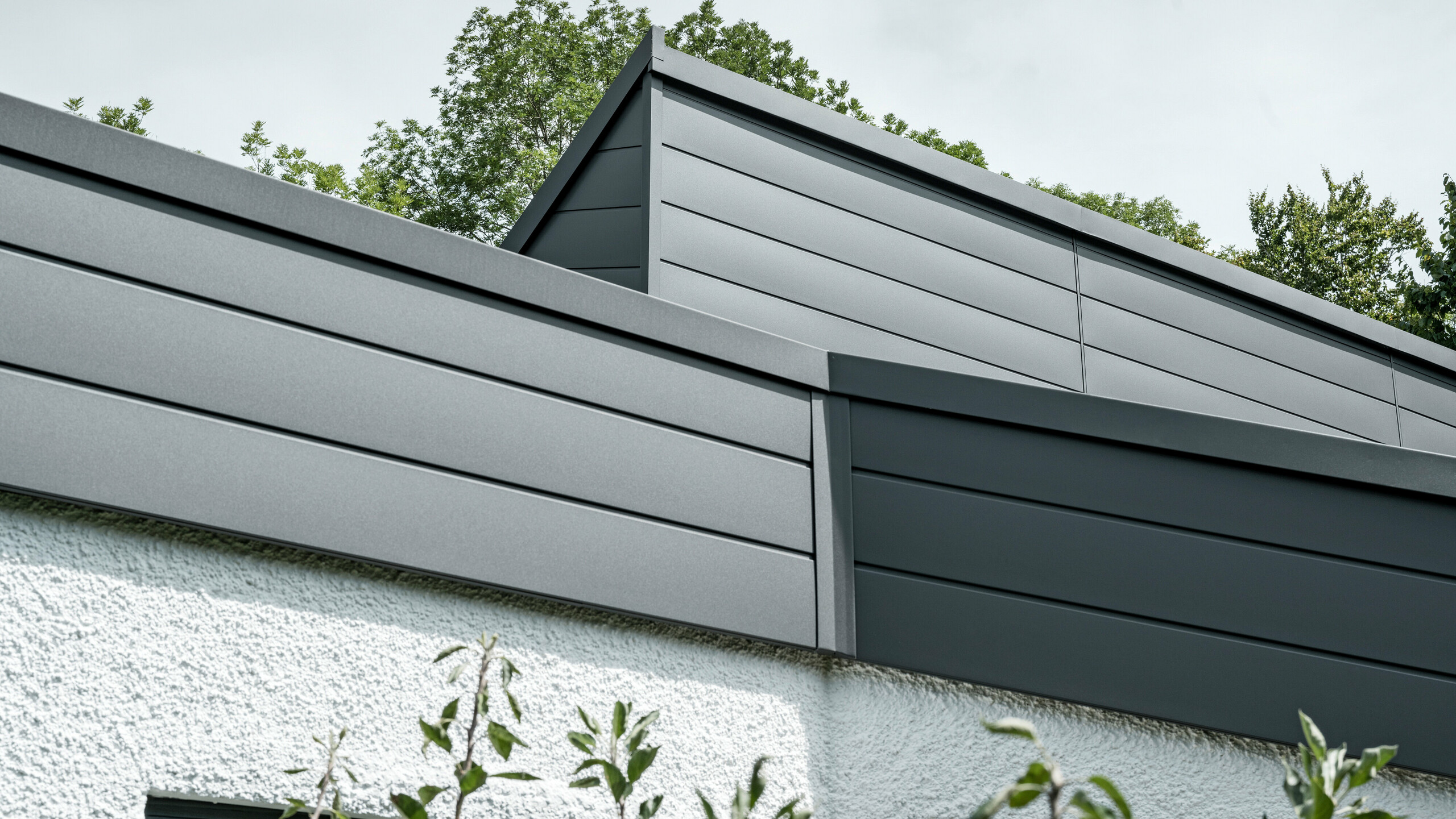 Ein Einfamilienhaus, das mit PREFA Dachschindeln DS.19 in schwarz eingedeckt wurde. Für Teile der Fassade wurden PREFA Sidings in P.10 dunkelgrau verwendet. 