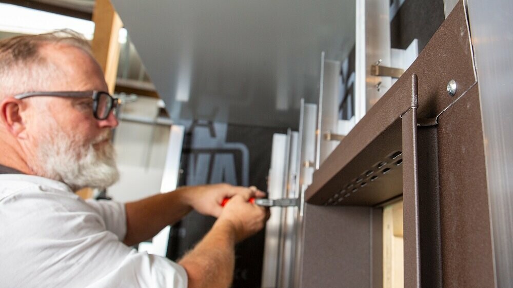 Die Aufnahme zeigt einen PREFA Techniker, der an der Fenstereinfassung mit Taschenprofilen ohne sichtbare Befestigung arbeitet.