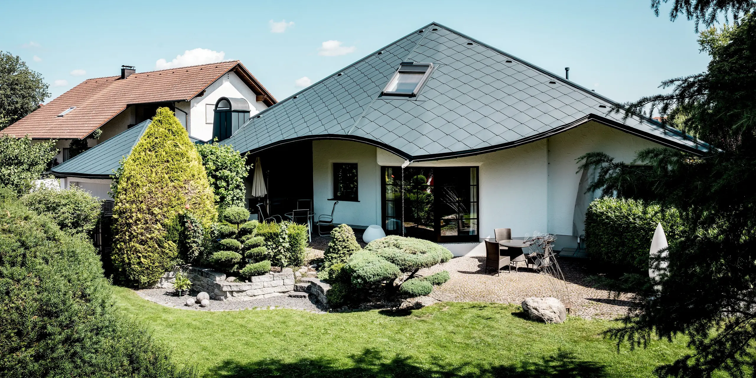 Das sanierte Einfamilienhaus in Bobingen begeistert mit seiner weit geschwungenen Dachlandschaft und der markanten PREFA Dachraute 44 × 44 in P.10 Anthrazit. Das elegante Rautenmuster betont die dynamische Form des Daches. Leichtes, robustes und witterungsbeständiges Aluminium bietet dabei langlebigen Schutz und große Gestaltungsfreiheit bei komplexen Dachgeometrien.