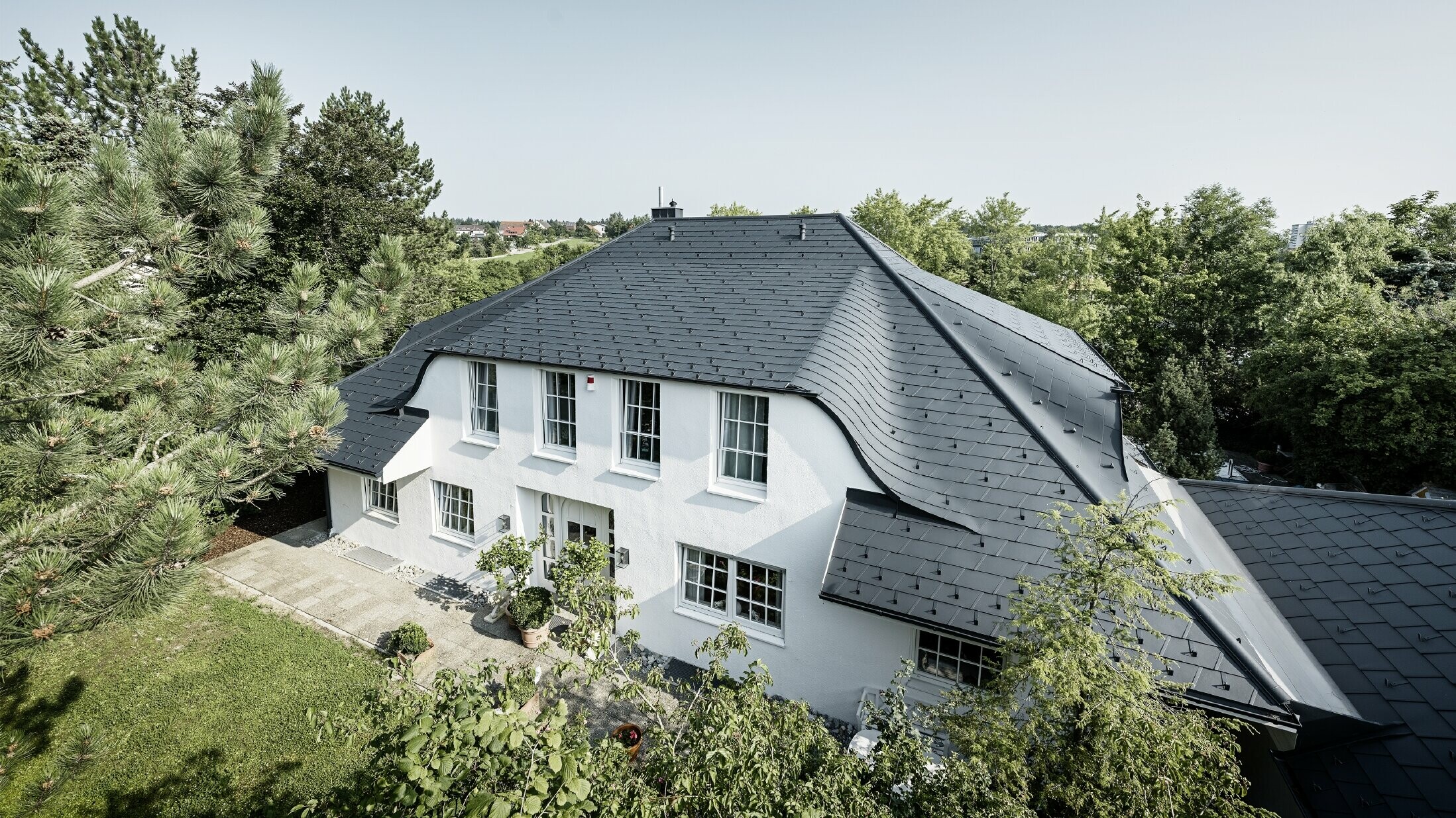 Walmdach mit vielen geschwungenen Gauben, eingedeckt mit der Aluminium Dachschindel DS.19 in Anthrazit