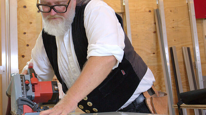 Tom Weiß sägt die angezeichneten Verbundplatten mittels Kreissäge auf Maß.