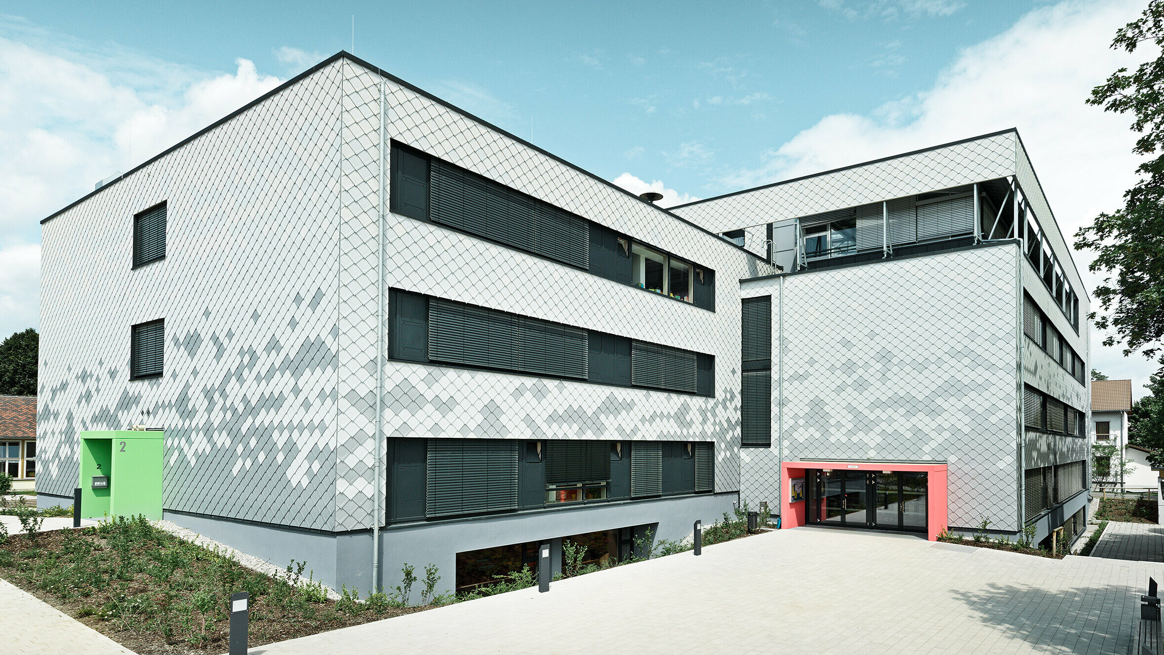Deutsche Mittelschule mit neuer Fassade, verkleidet mit PREFA Wandrauten in drei verschiedenen Farben