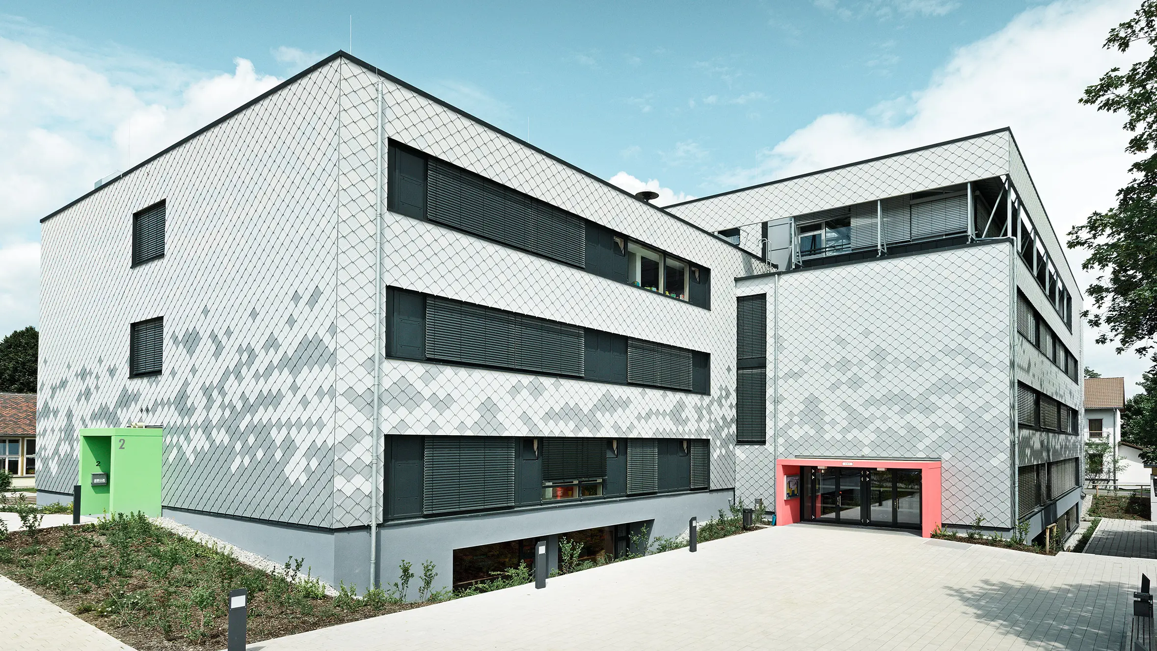 Deutsche Mittelschule mit neuer Fassade, verkleidet mit PREFA Wandrauten in drei verschiedenen Farben