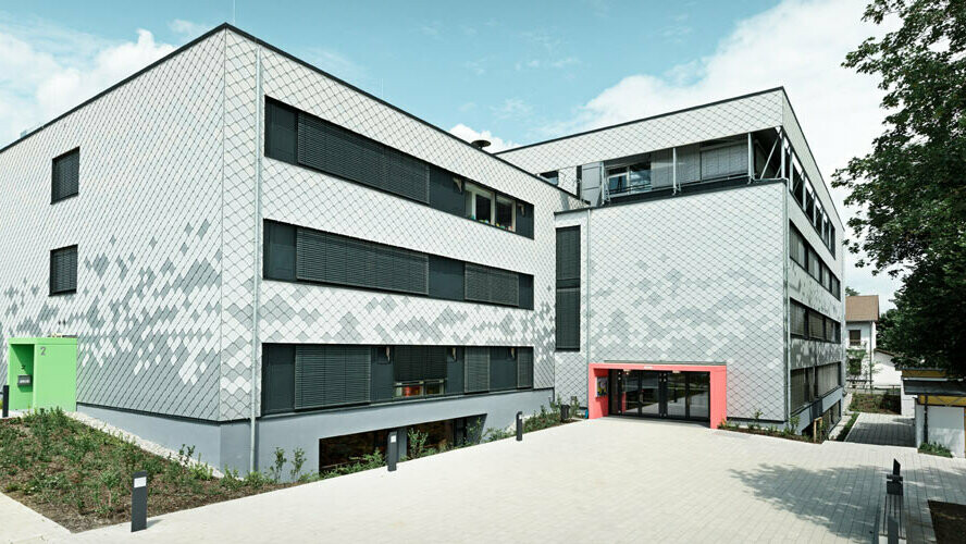 Deutsche Mittelschule mit neuer Fassade, verkleidet mit PREFA Wandrauten in drei verschiedenen Farben