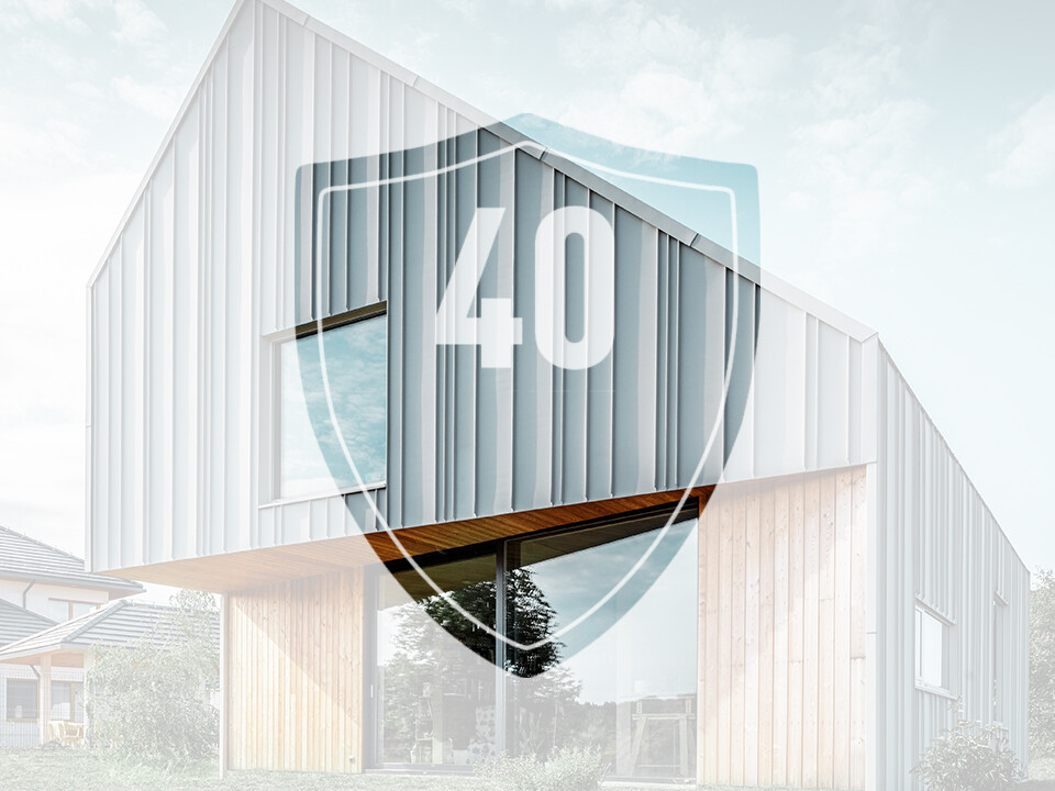 Das Bild zeigt ein Schild mit der Zahl "40", welche die Garantie auf PREFA Aluminiumprodukte darstellen soll, vor einem modernem Einfamilienhaus.