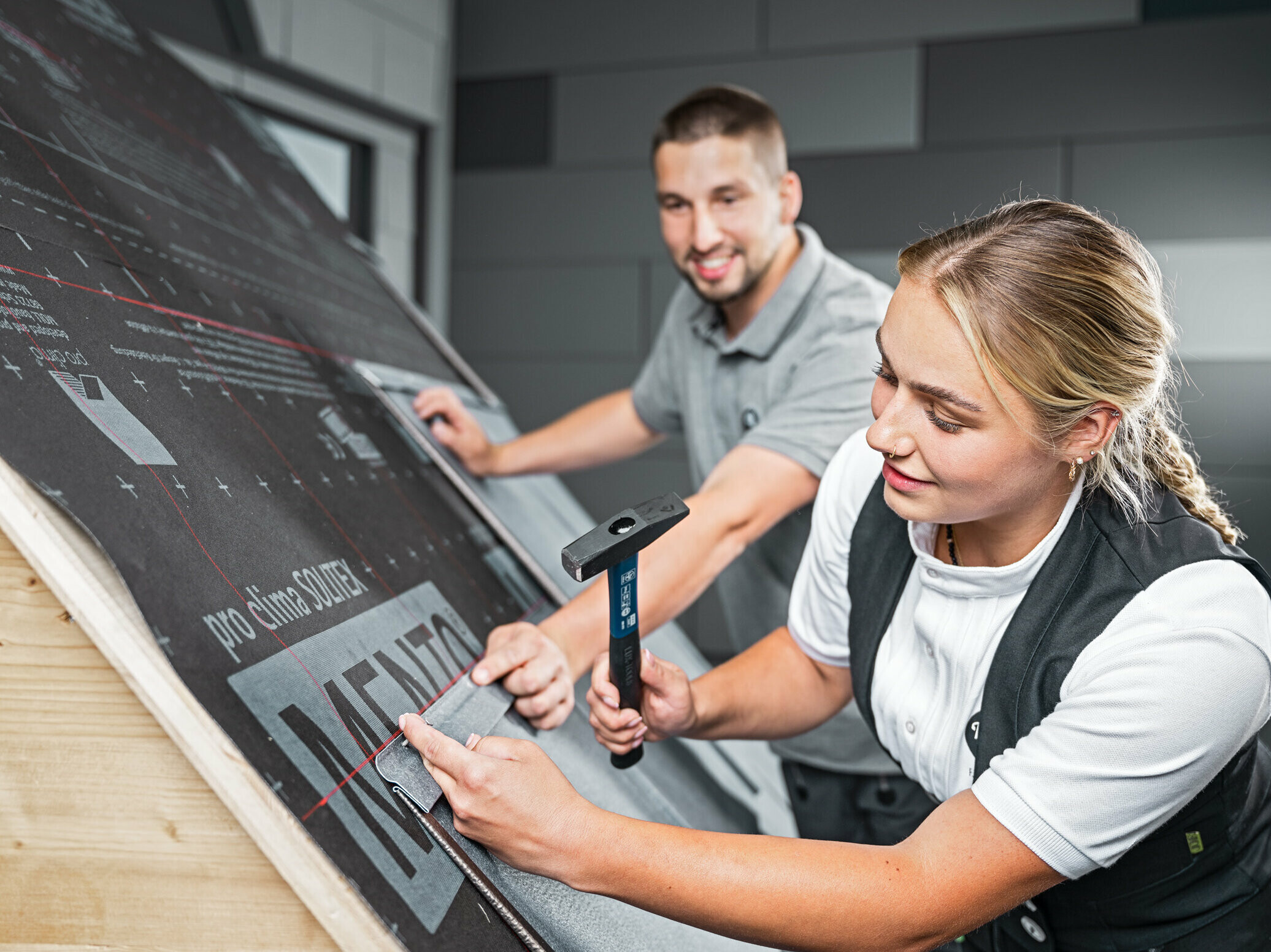 Dachdeckermeisteriin Fabienne verlegt unter der Aufsicht von PREFA Lehrverleger Julian Eickhoff die Dachplatte R.16 auf ein Dachmodell in der PREFA Academy in Rheinbach. 