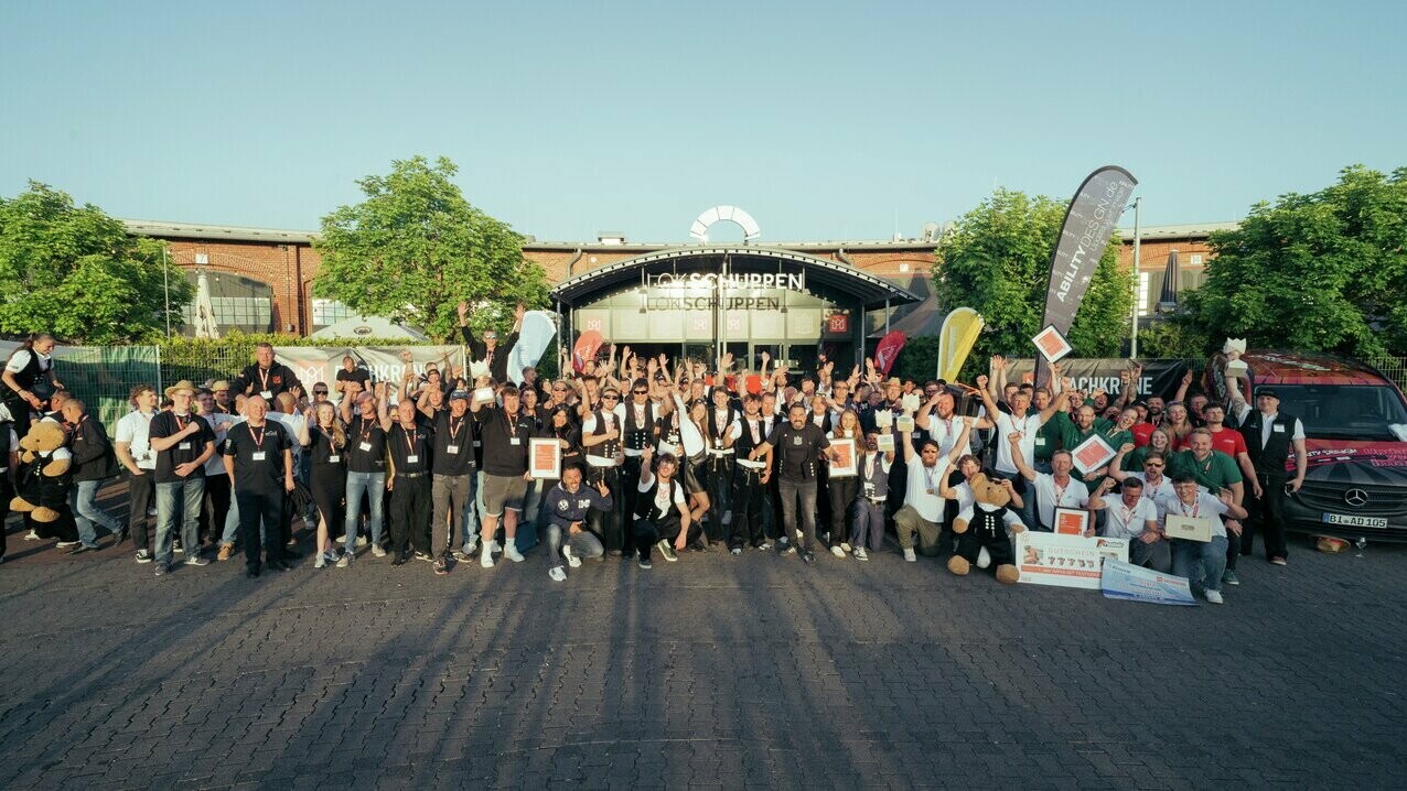 Strahlende Gesichter und erhobene Pokale: Beim Gruppenfoto vor dem Lokschuppen Bielefeld versammeln sich alle Teilnehmerinnen, Gewinnerinnen, Partner und Unterstützer der Dachkrone 2025.