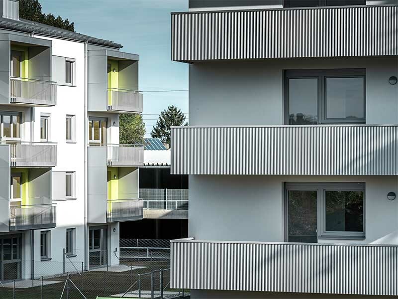 Moderne Wohnhausanlage in St. Pölten, die in den Farben Weiß, Silbermetallic und grünen Akzenten gestaltet wurde.