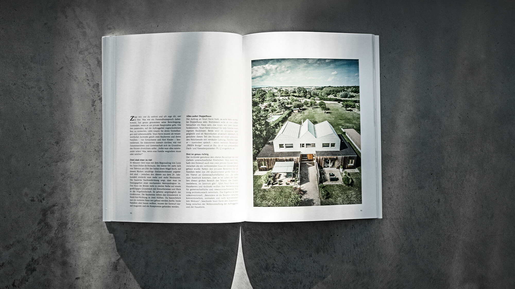 Das geöffnete PREFARENZEN Buch 2024 mit einem Beitrag über das Doppelhaus von Youri Favre Architecture vor einem grauen Hintergrund.