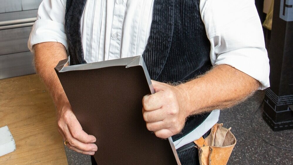 Der PREFA Techniker hält die selbst erstelle Fensterbank mit wasserdichter Quetschfalte in der Hand.