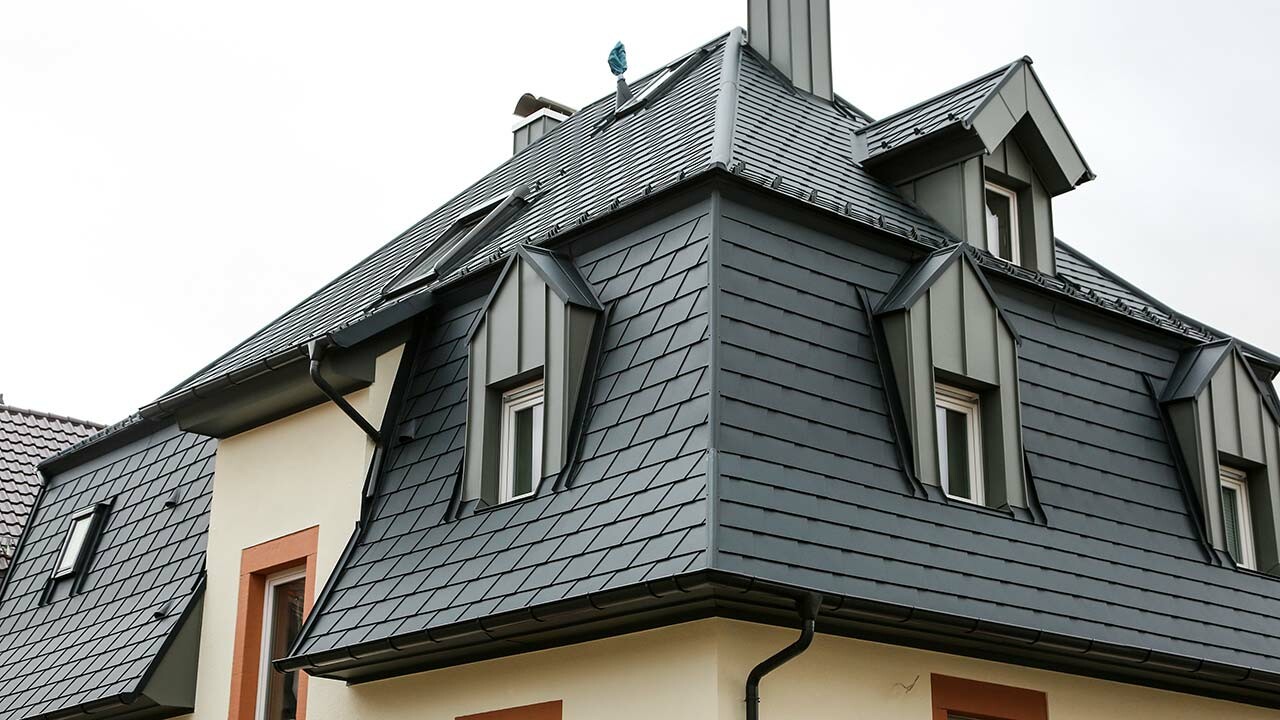 Detailaufnahme des neu sanierten Daches in Heppenheim, eingedeckt mit der PREFA Dachschindel in Anthrazit, zu sehen sind viele Details wie Gauben, Mansarden und Fenster