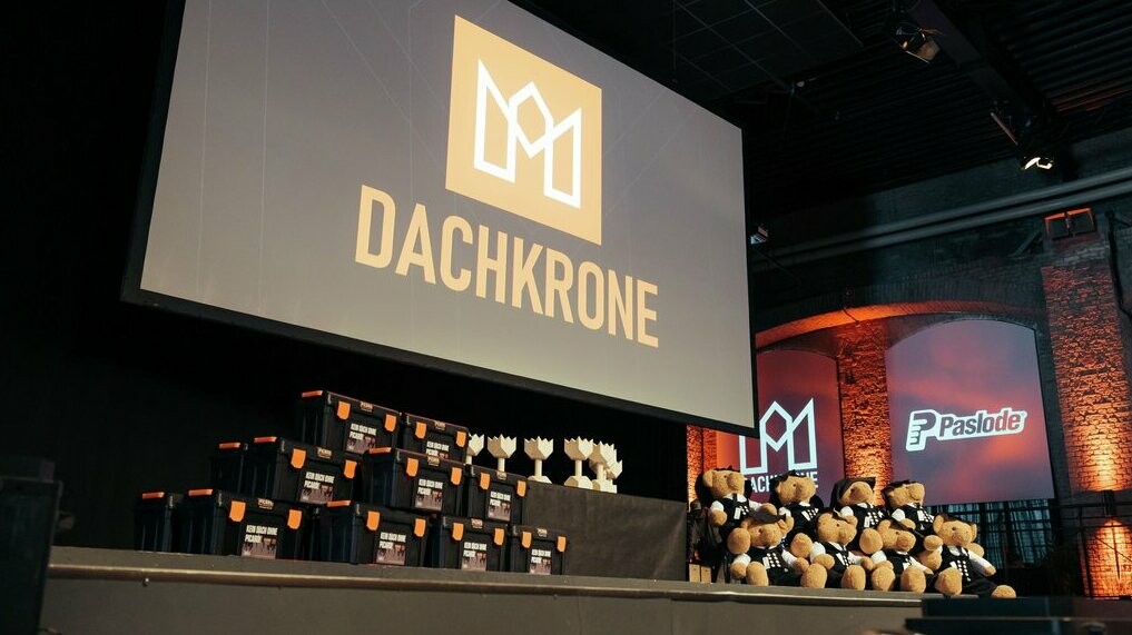 Die Bühne der Dachkrone 2025 vor Beginn der Preisverleihung - Pokale, Geschenkboxen und Maskottchen warten auf die Preisträger. Das zentrale Logo und moderne Lichtinszenierungen schaffen eine feierliche Atmosphäre.