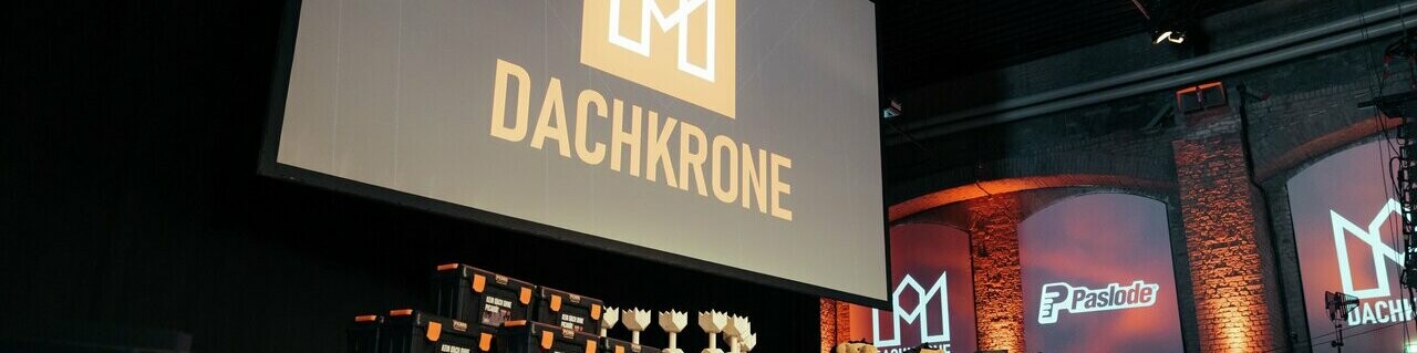 Die Bühne der Dachkrone 2025 vor Beginn der Preisverleihung - Pokale, Geschenkboxen und Maskottchen warten auf die Preisträger. Das zentrale Logo und moderne Lichtinszenierungen schaffen eine feierliche Atmosphäre.