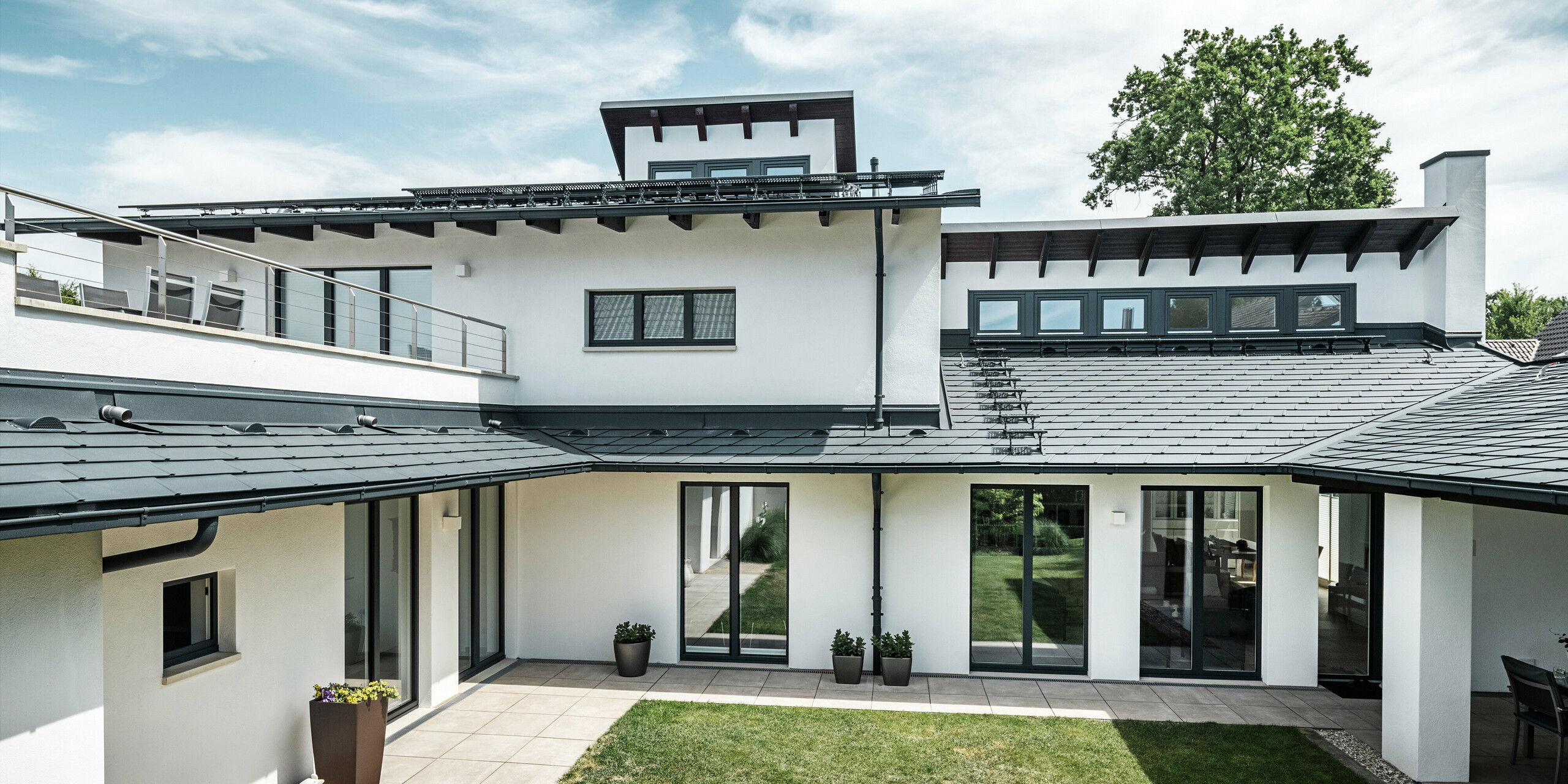 Zu sehen ist der Innenhof eines Einfamilienhauses in Dortmund, welches mit PREFA Dachschindeln DS.19 und PREFALZ in der Farbe P.10 Anthrazit eingedeckt wurde.