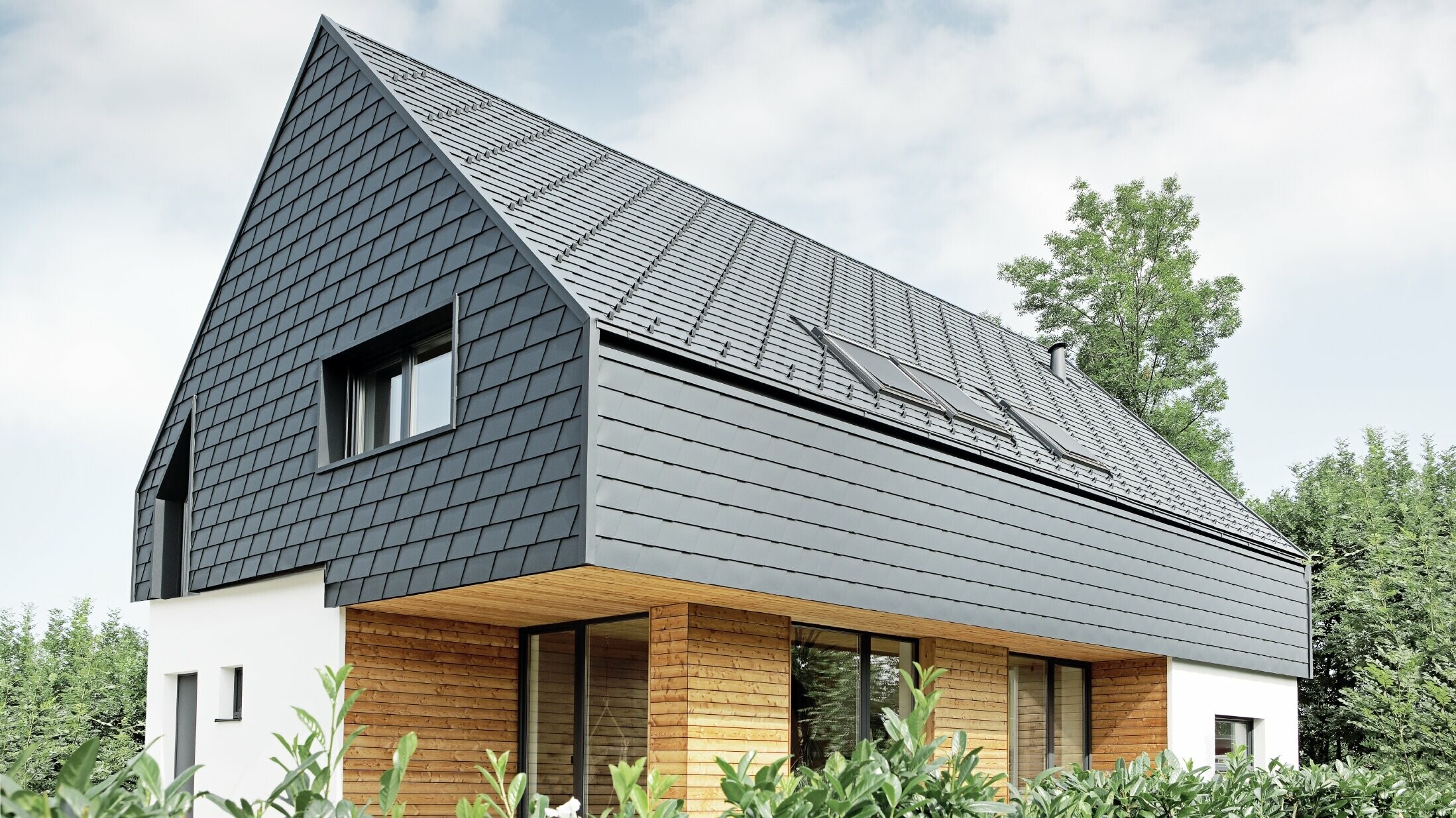 Einfamilienhaus mit Satteldach, eingedeckt mit der PREFA Schindel in P.10 Anthrazit, auch an der Fassade im Obergeschoß und am Giebel wurde die Schindel verlegt