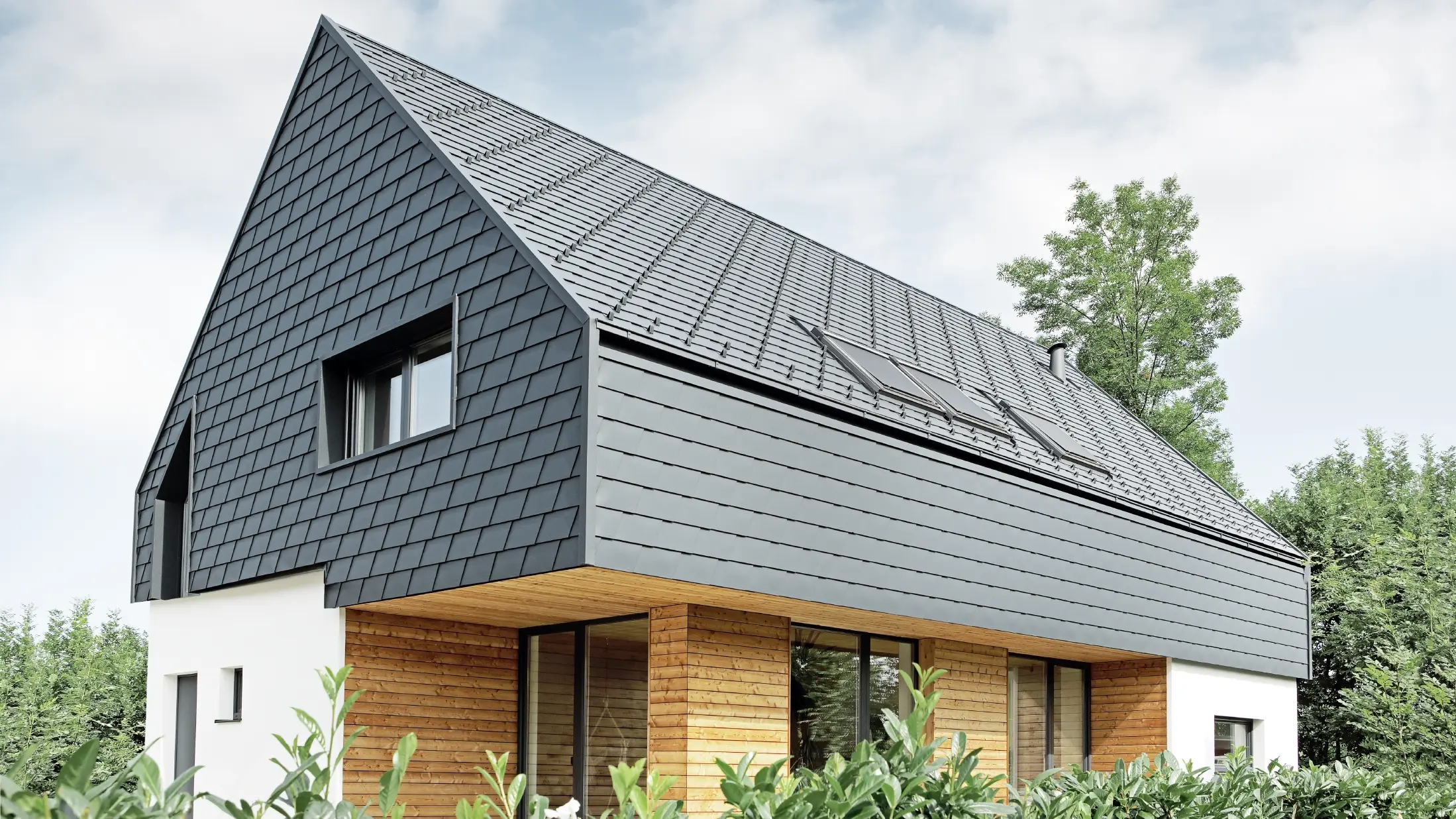 Einfamilienhaus mit Satteldach, eingedeckt mit der PREFA Schindel in P.10 Anthrazit, auch an der Fassade im Obergeschoß und am Giebel wurde die Schindel verlegt