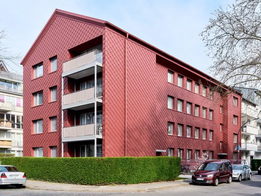 Serielles Sanierungsprojekt eines bewohnten Mehrfamilienhauses in Deutschland, das nach dem niederländischen Energiesprong-Prinzip zum Passivhaus Plus bzw. Net-Zero-Standard umgebaut wurde. Die Fassade besteht aus Rauten 29x29 in 05 P.10 Oxydrot.