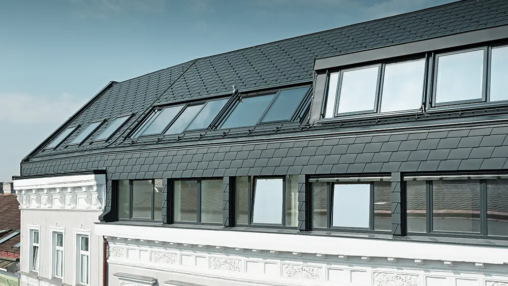 Dachgeschossausbau einer Wohnhausanlage in Wien mit der Dachschindel in P.10 Anthrazit