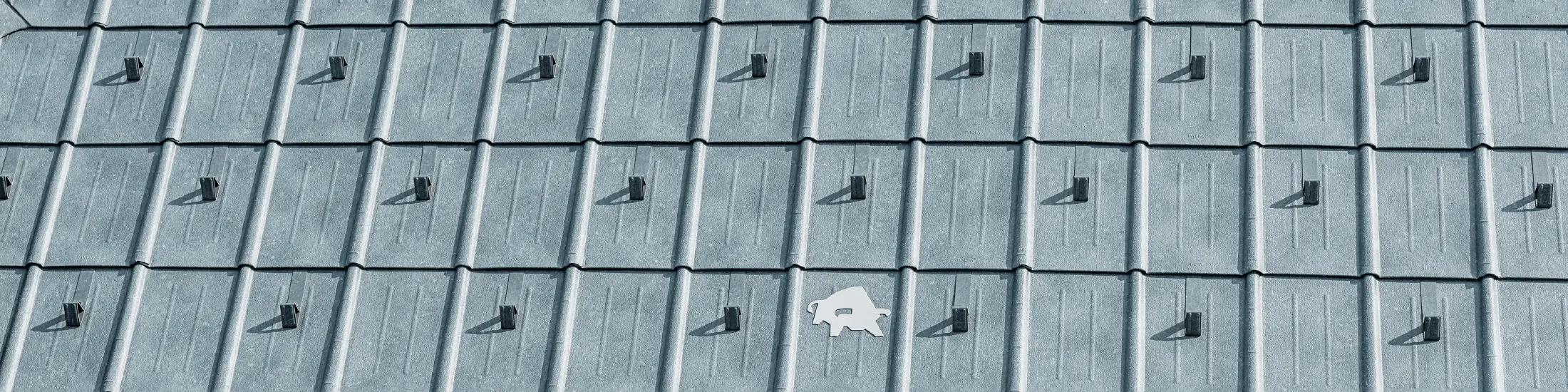 PREFA Dachplatte mit PREFA-Stierlogo in der Farbe P.10 Steingrau; Dachoberfläche mit PREFA Blechdach.